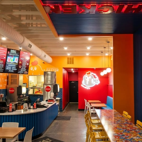 Vibrant interior of a fast-casual restaurant with orange, blue, and red walls, and a service counter.